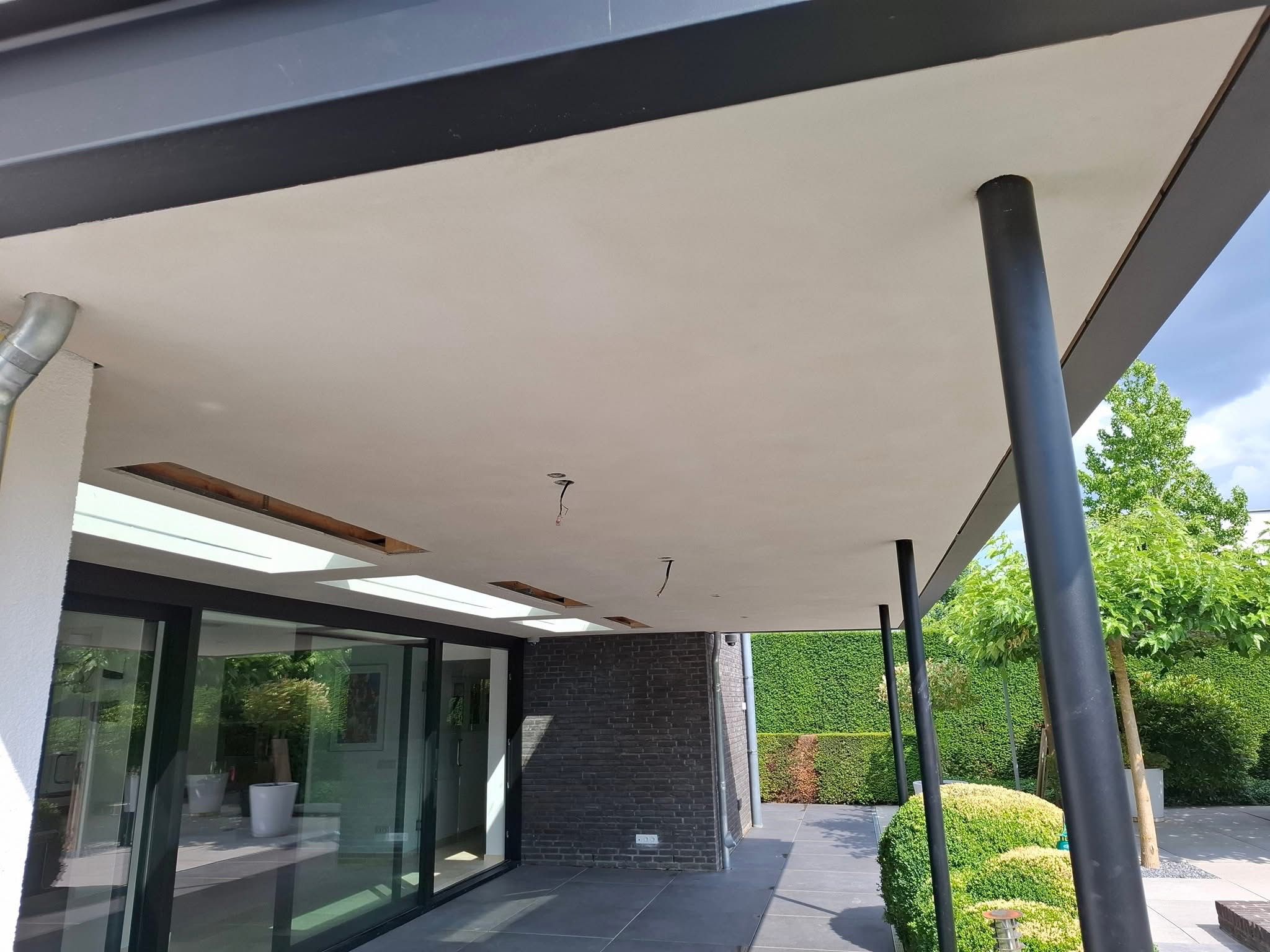 Overkapping met strak wit buitenplafond langs tuin en glasgevel